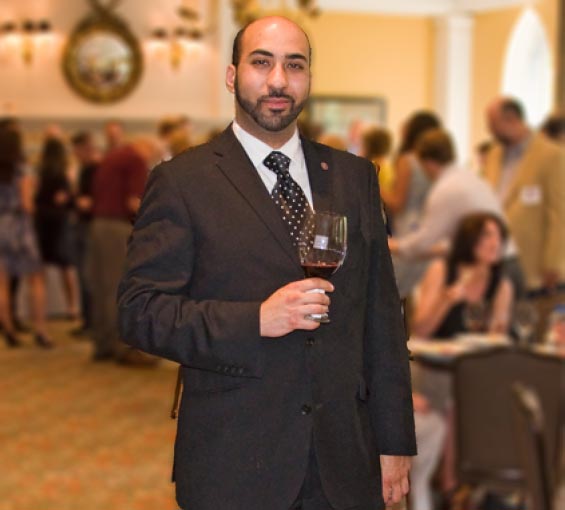 Impulse Wines founder: Yashar Shayan. In a suit and holding a glass of wine. 